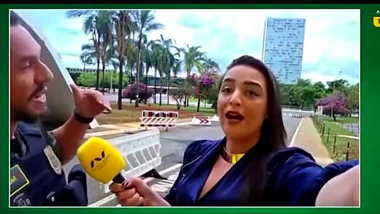 Déborah Sena fala para a câmera durante a abordagem da Polícia Legislativa, com o microfone da Auri Verde Brasil