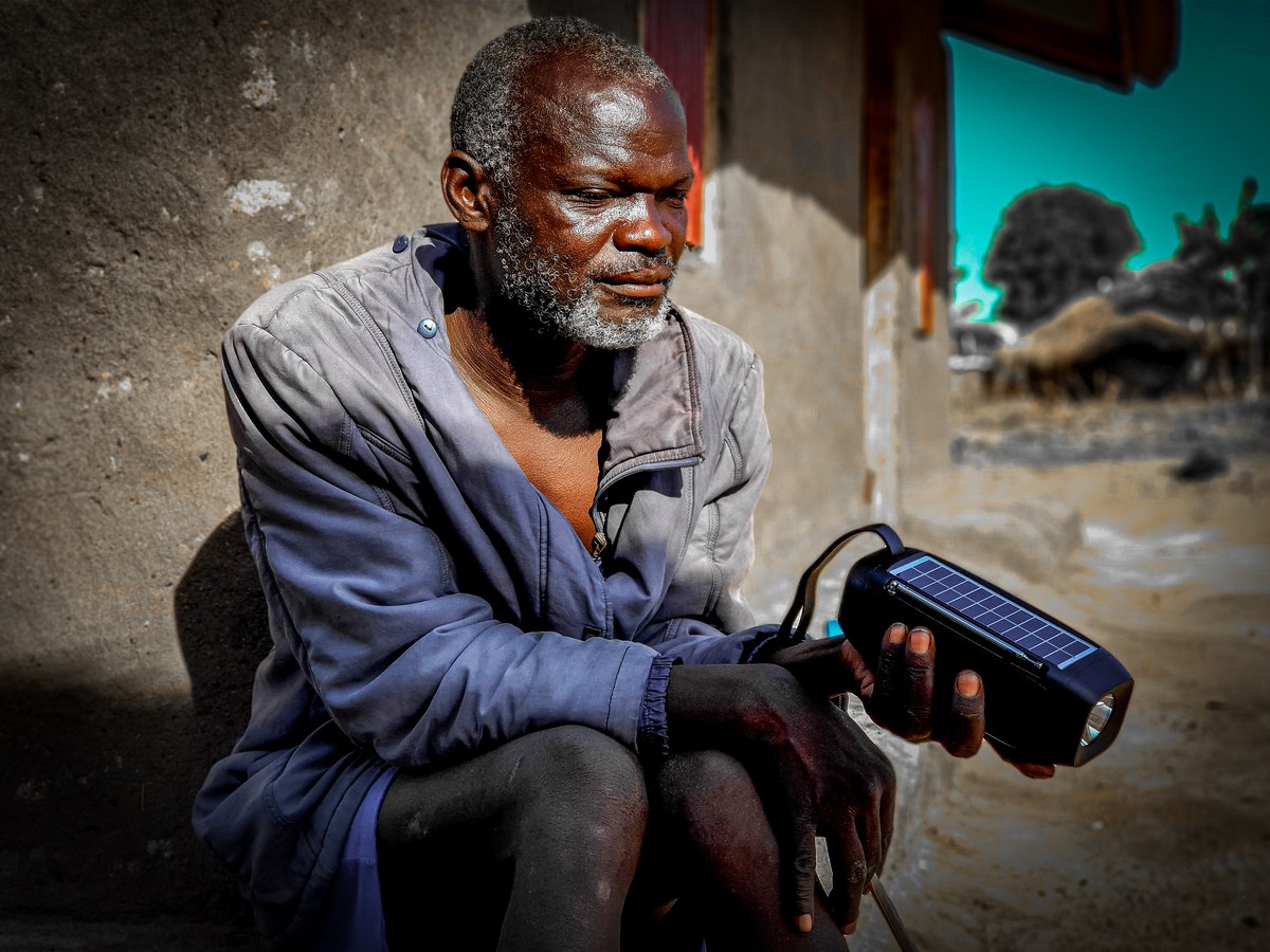 missionários entregam 750 Bíblias em áudio no Congo, e a imagem mostra um homem ouvindo rádio em casa na África, em referência aos aparelhos solares distribuídos em Bunia