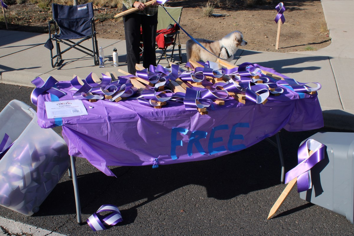 pai que parou atirador em escola do Oregon na Silver Rail Elementary, e a imagem mostra uma mesa com fitas roxas de memorial distribuídas em homenagem às vítimas da escola