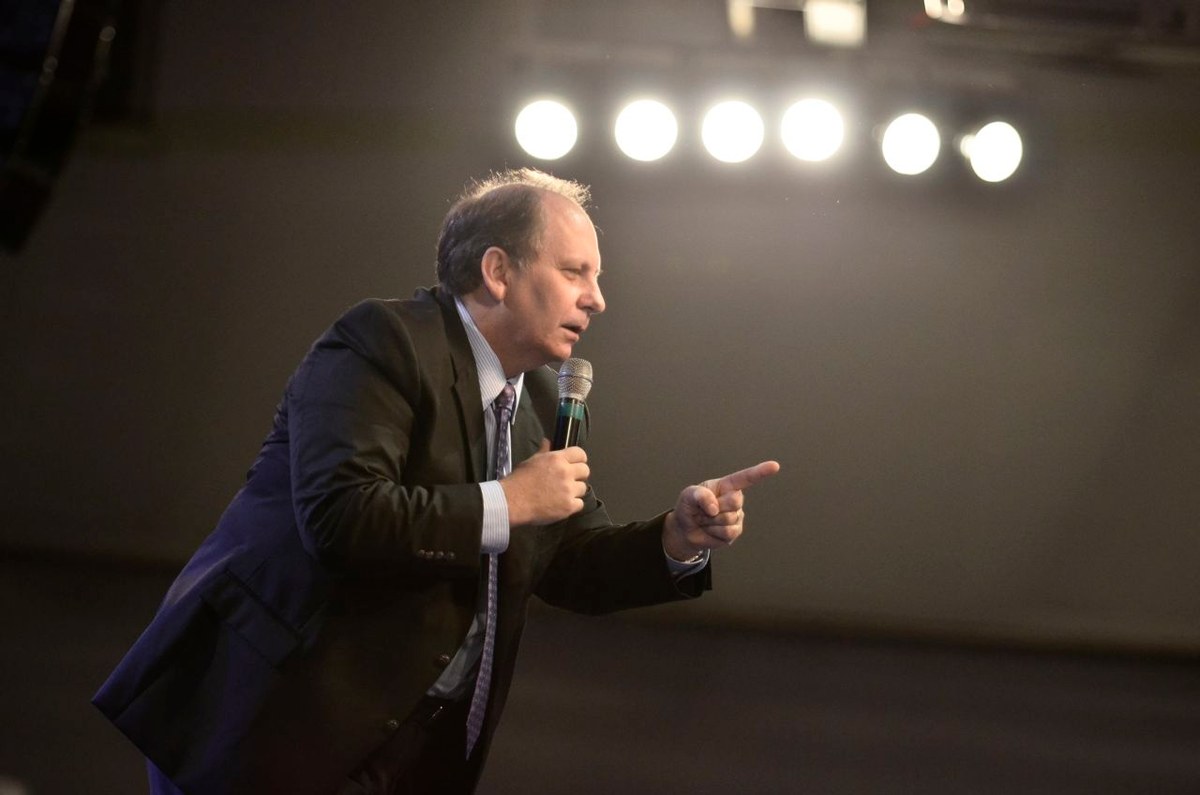 pastor Lamartine Posella pede orações após relatar fortes dores no ventre, e a imagem mostra o pastor Lamartine Posella pregando com microfone em um culto