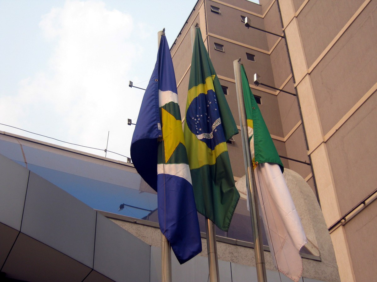 PF prende presidente do Tribunal de Contas de MT, e a imagem mostra as bandeiras do Brasil, de Mato Grosso e de Cuiabá hasteadas lado a lado