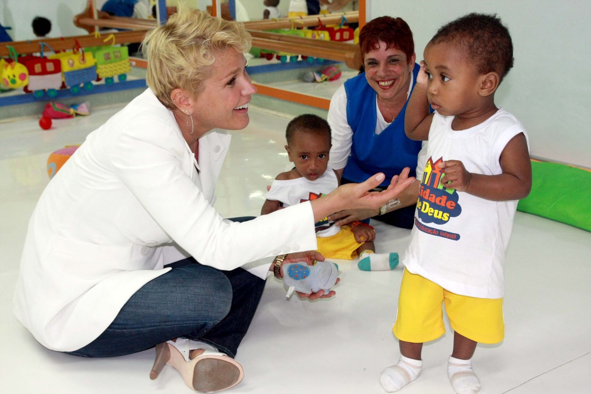 Xuxa Meneghel brincando com crianças na Cidade de Deus, no Rio de Janeiro, em 2011